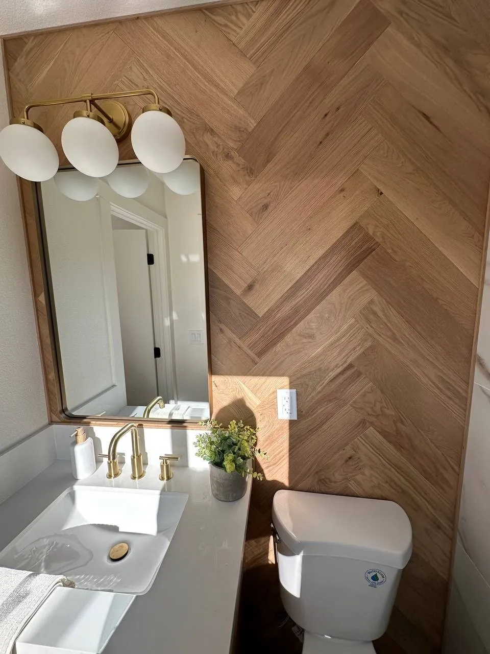 Herringbone wood accent wall behind a bathroom vanity