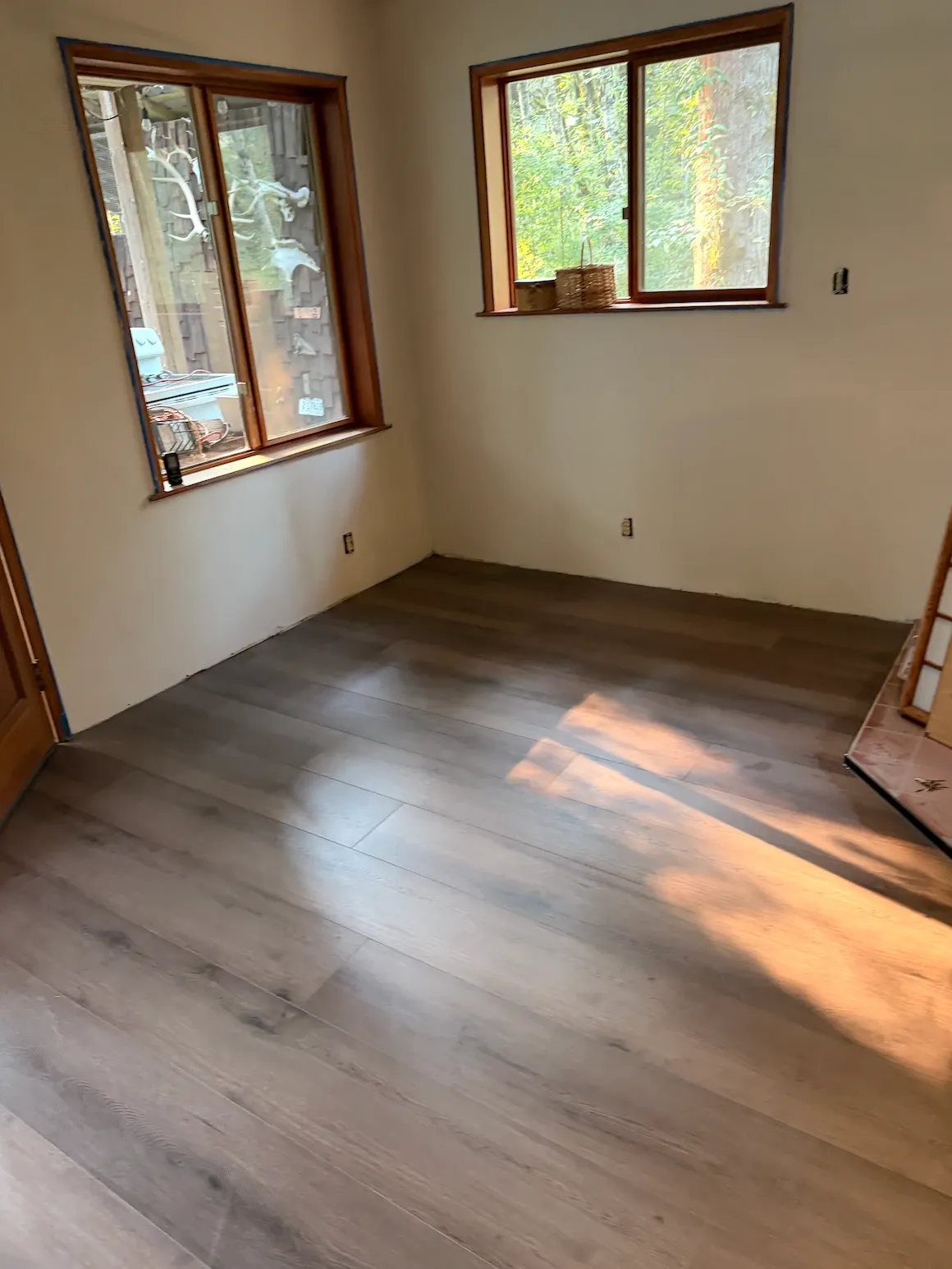 Vinyl plank flooring in a corner room with two wood-trimmed windows