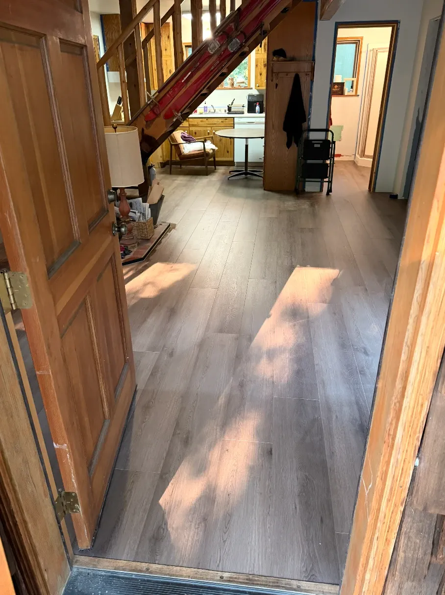 Wood-look vinyl plank running from the front door through the living area to the kitchen