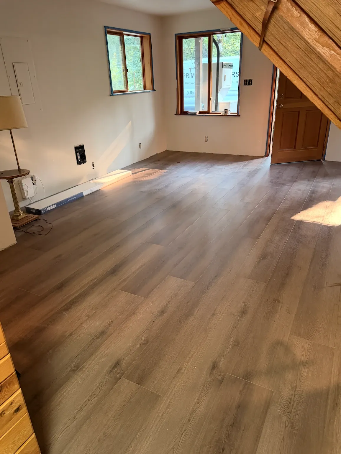 Vinyl plank across a living room, with a Prime Step Floors work van visible through the window