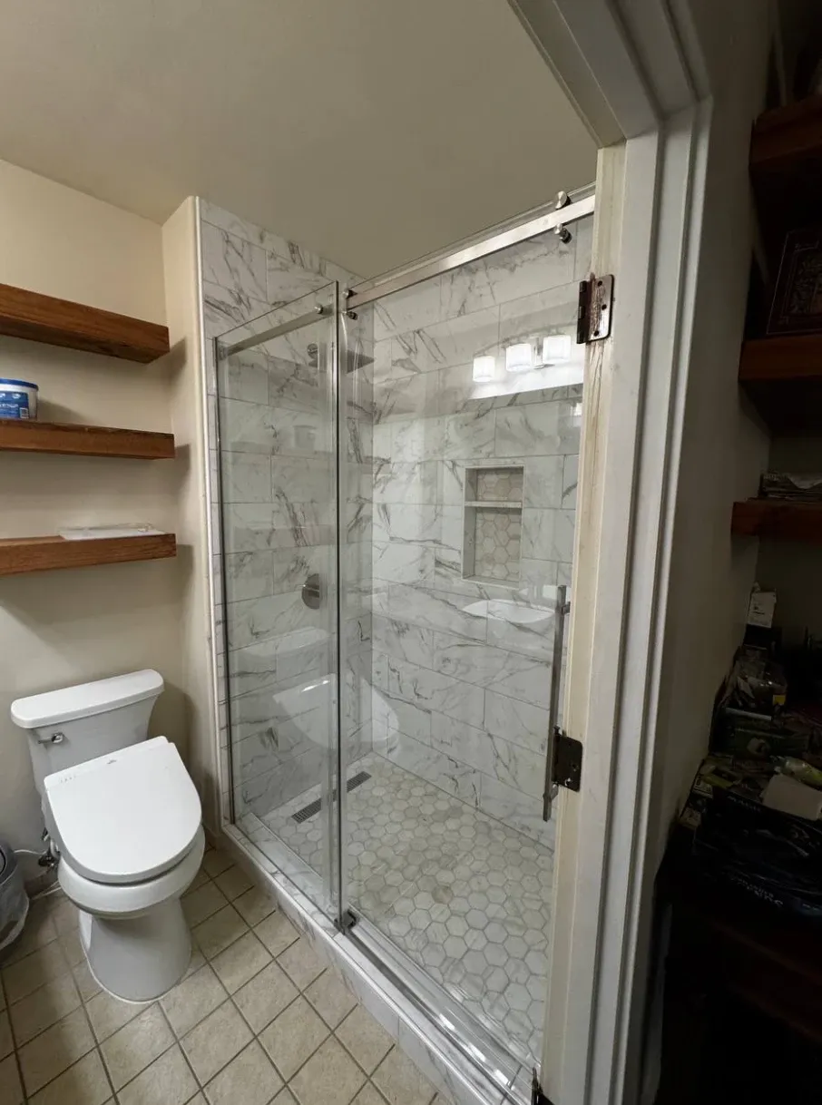 Walk-in shower with white marble-look wall tile, a hexagon mosaic floor, a linear drain and a tiled niche behind a sliding glass door