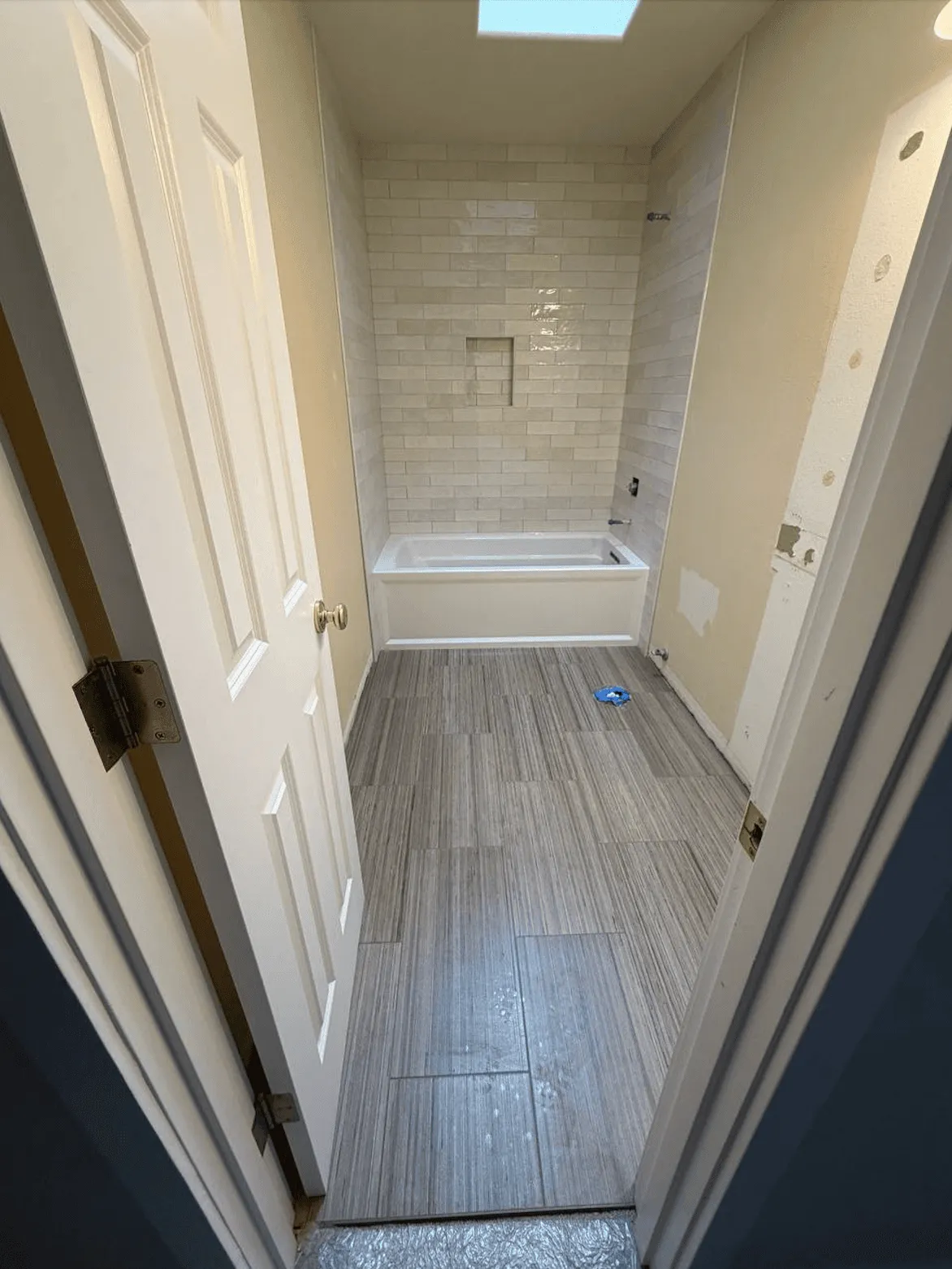 Plank flooring in a hallway leading into a bathroom