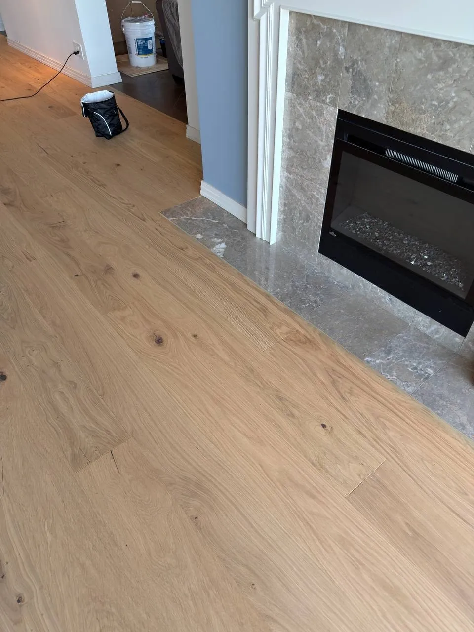 Wide-plank wood floor fitted around a fireplace hearth